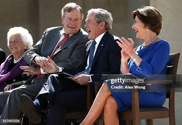 Former U.S. President George W. Bush shakes hands with his father former President George H.W. Bush as they attend the opening ceremony of the George...