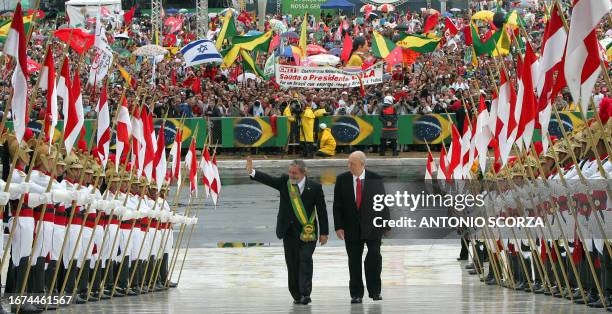 Brazilian President Luiz Inacio Lula da Silva waves as he climbs up the Planalto Palace's ramp beside Vice-president Jose Alencar Gomes da Silva,...