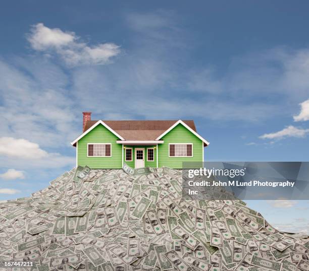 house sitting on pile of dollar bills - haus geld stock-fotos und bilder