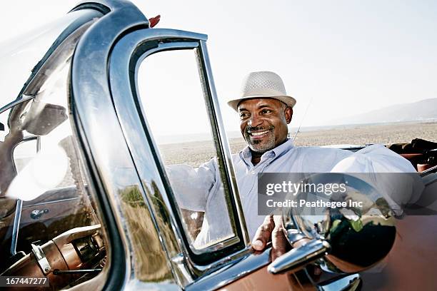 black man driving convertible - voiture de collection photos et images de collection