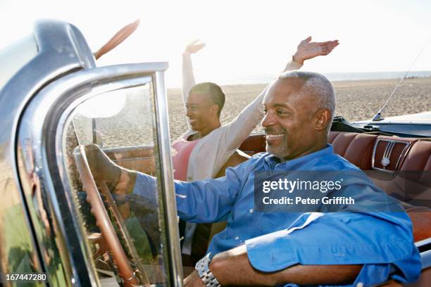 black couple driving convertible - couple on the beach with car stockfoto's en -beelden