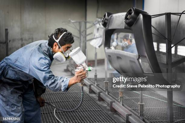 worker spray painting in manufacturing plant - side part photos et images de collection