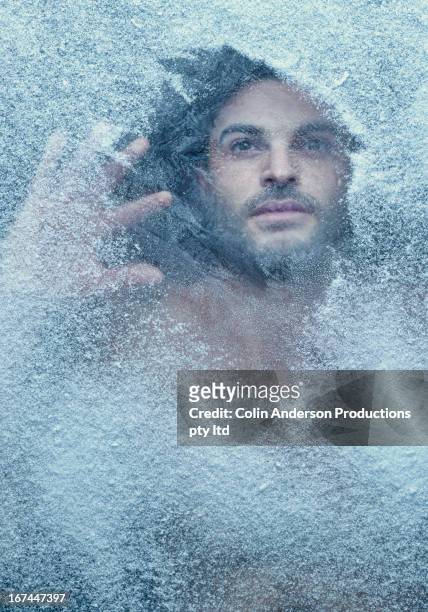 hispanic man behind snow covered window - freezing cold stockfoto's en -beelden