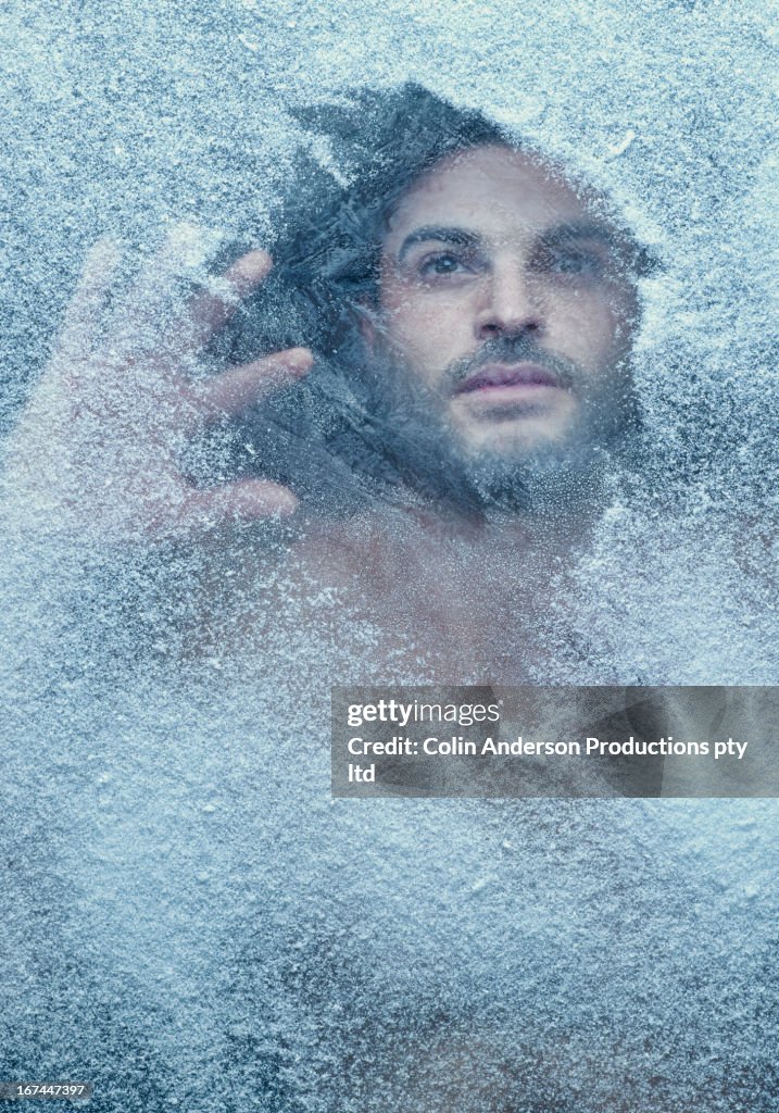 Hispanic man behind snow covered window