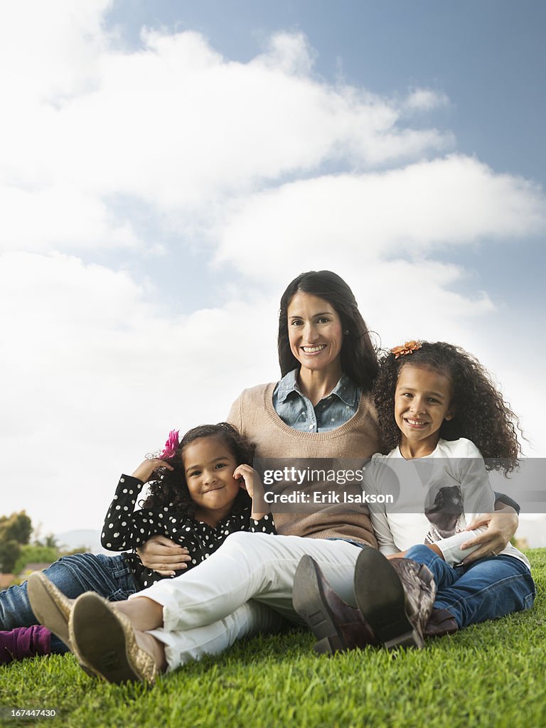 Mother and daughters sitting in grass