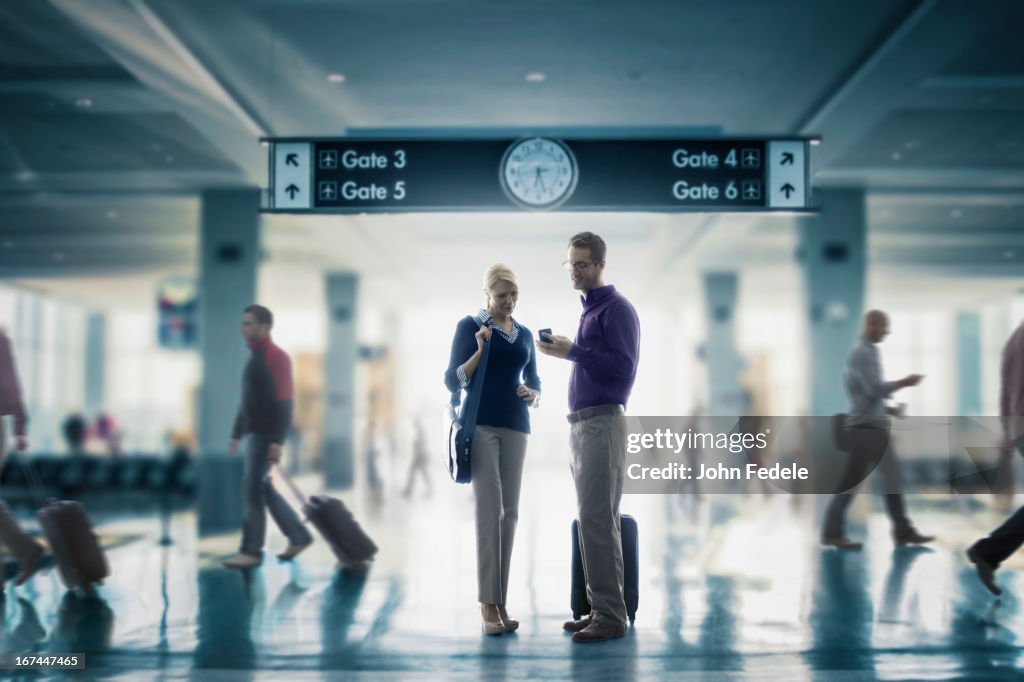 Caucasian couple looking at cell phone in airport