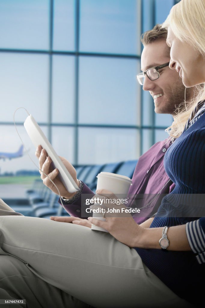 Caucasian couple using digital tablet in airport