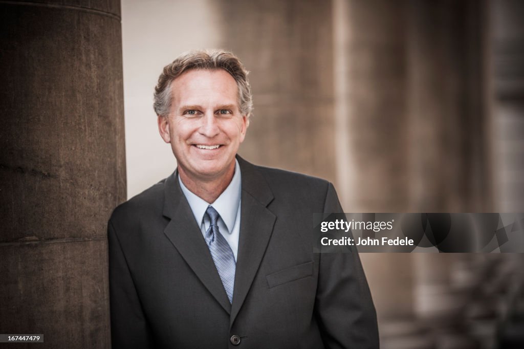 Caucasian businessman leaning on pillar