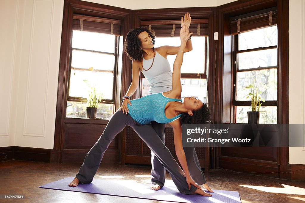 Mixed race women practicing yoga in living room