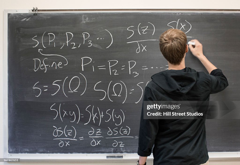 Caucasian student writing on blackboard