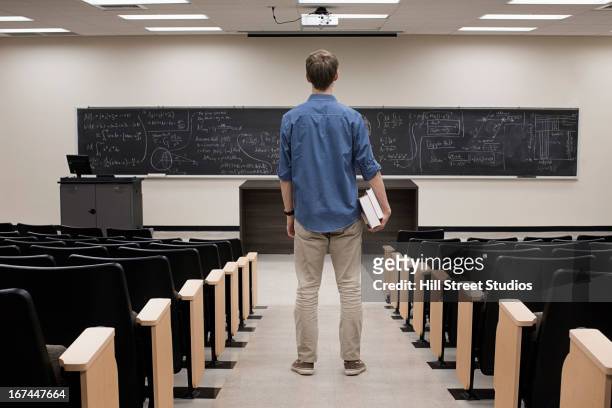 caucasian student standing in classroom - universiteit stockfoto's en -beelden