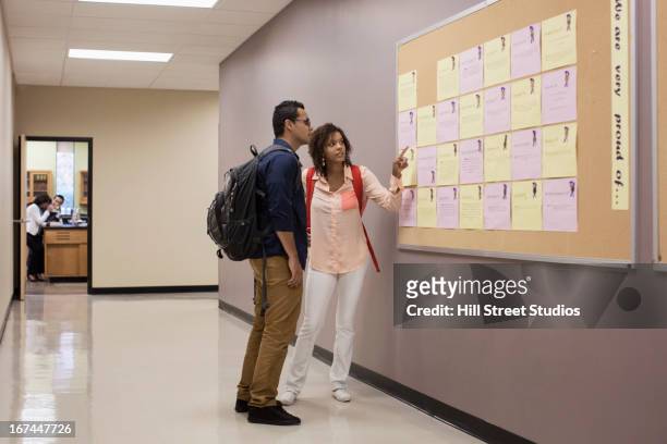students reading bulletin board in hallway - bulletin stock pictures, royalty-free photos & images