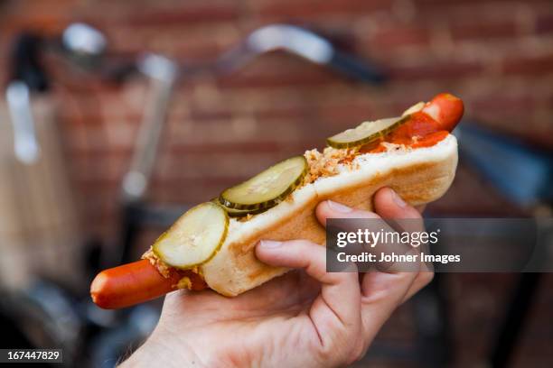 hand holding hot dog - hotdog stockfoto's en -beelden