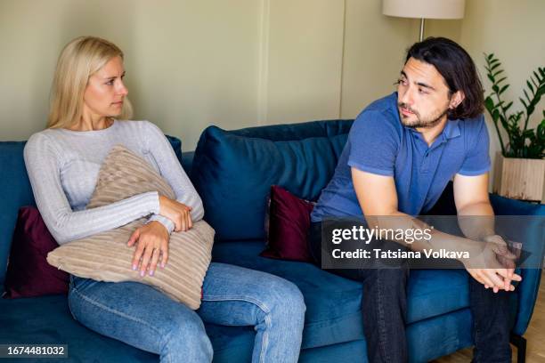 photo of frustrated married couple sitting on sofa and looking at each other in marriage counselor office - kommunikationsproblem stock-fotos und bilder