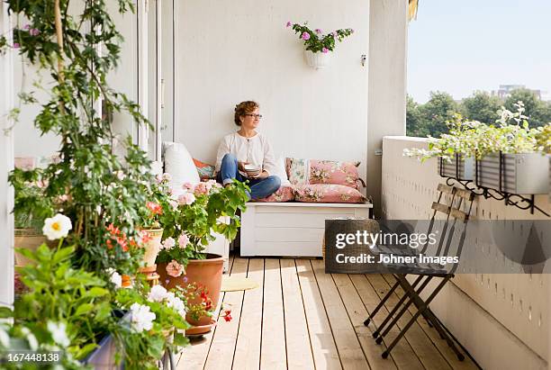 woman relaxing on balcony - té terraza fotografías e imágenes de stock