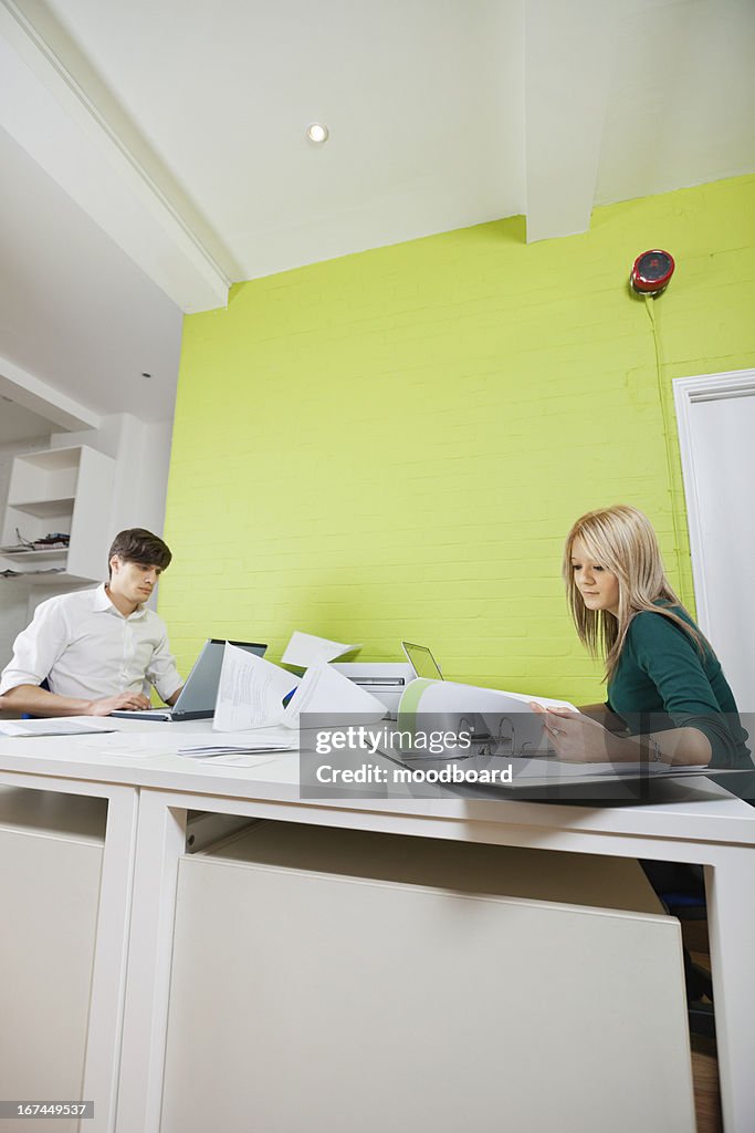 Side view of young businesspeople busy working at desk