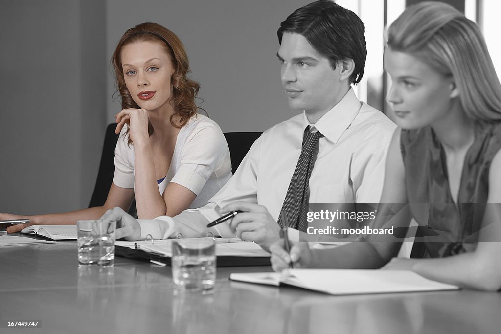 Portrait of young businesswoman with colleagues in a meeting