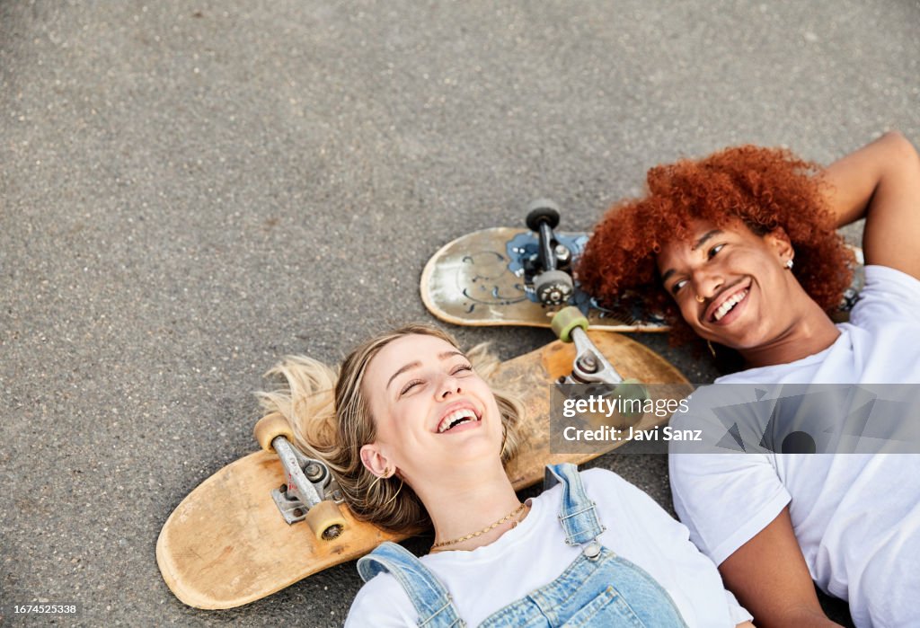 Top view of happy young hipster skater friends lying on a road