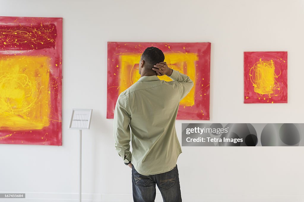 Man watching paintings in modern art gallery