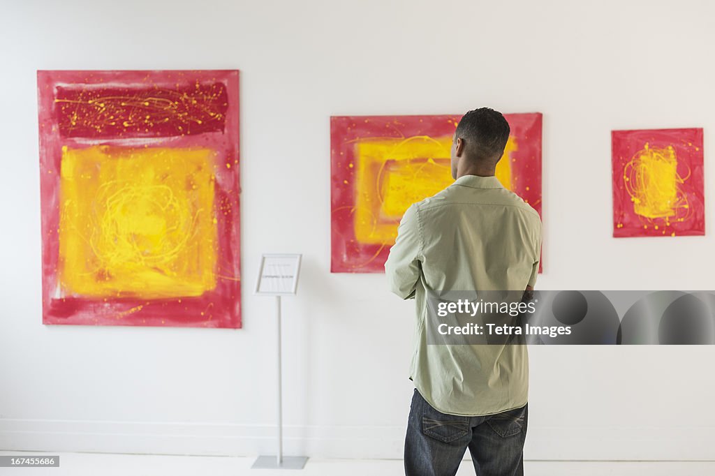 Man watching paintings in modern art gallery