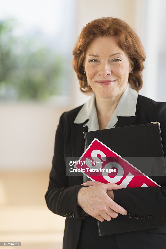 USA, New Jersey, Jersey City, Portrait of female real estate agent holding sold sign