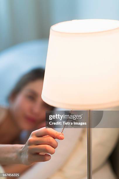 usa, new jersey, jersey city, woman turning off lamp - nachttischlampe stock-fotos und bilder