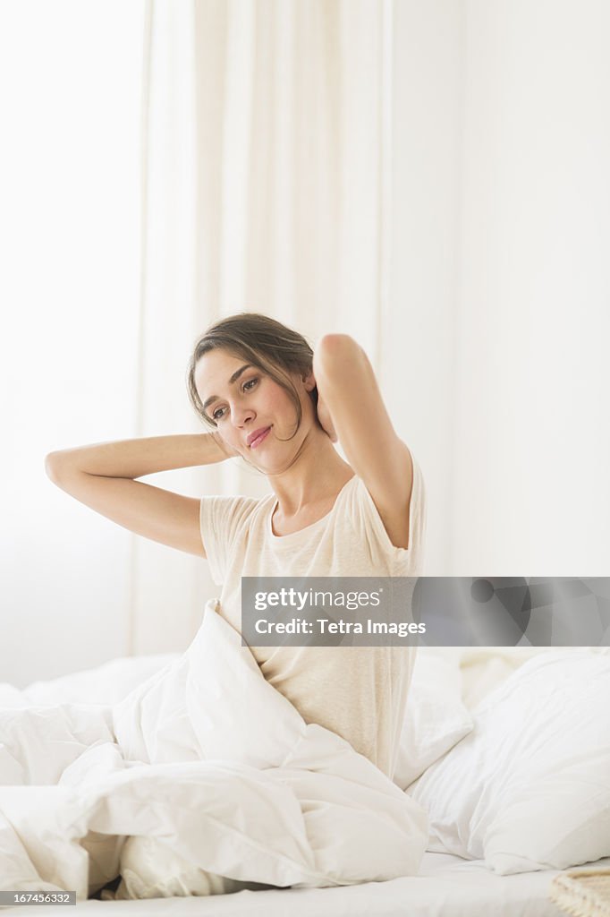 USA, New Jersey, Jersey City, Woman stretching on bed