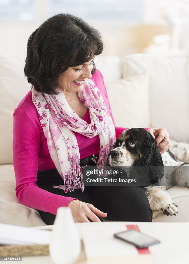 USA, New Jersey, Jersey City, Portrait of senior woman sitting on sofa with her dog