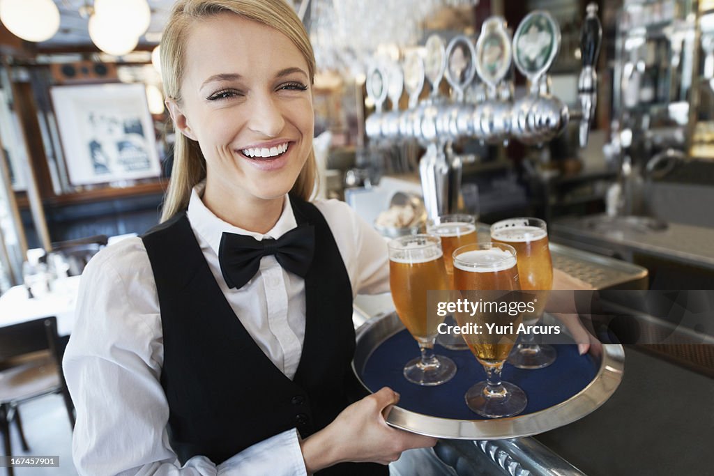 Denmark, Aarhus, Portrait of young woman holding tray with beer glasses