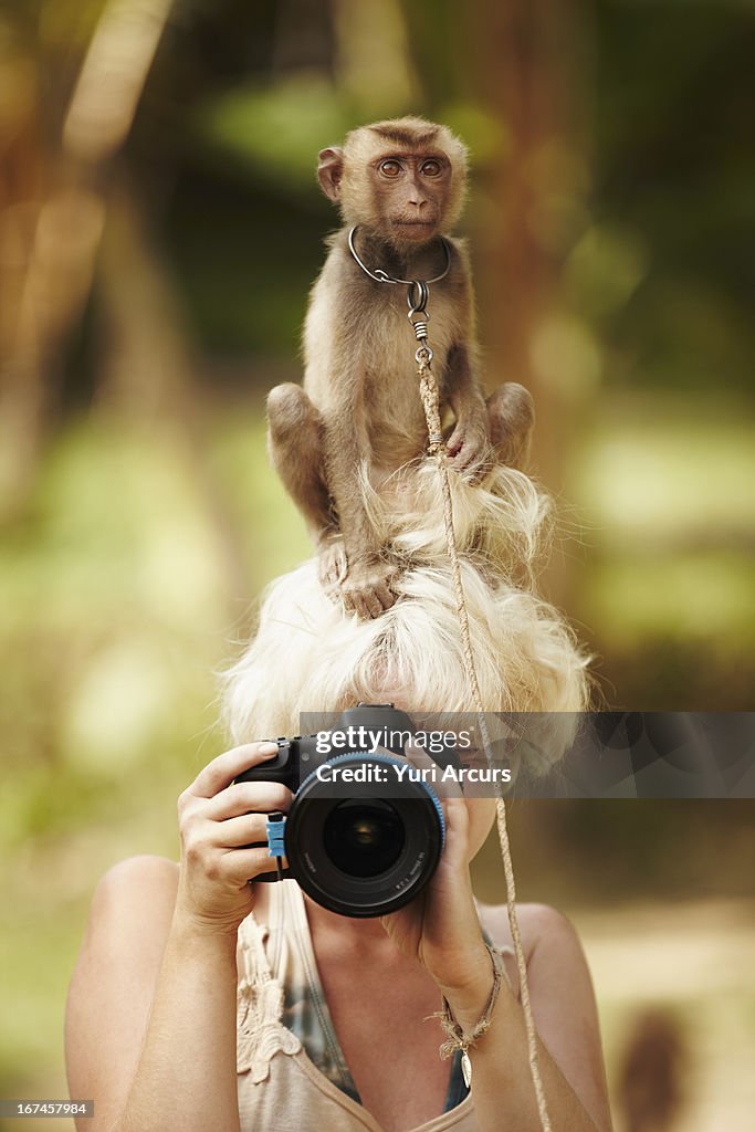 Thailand, Portrait of female photographer with macaque monkey sitting atop her head