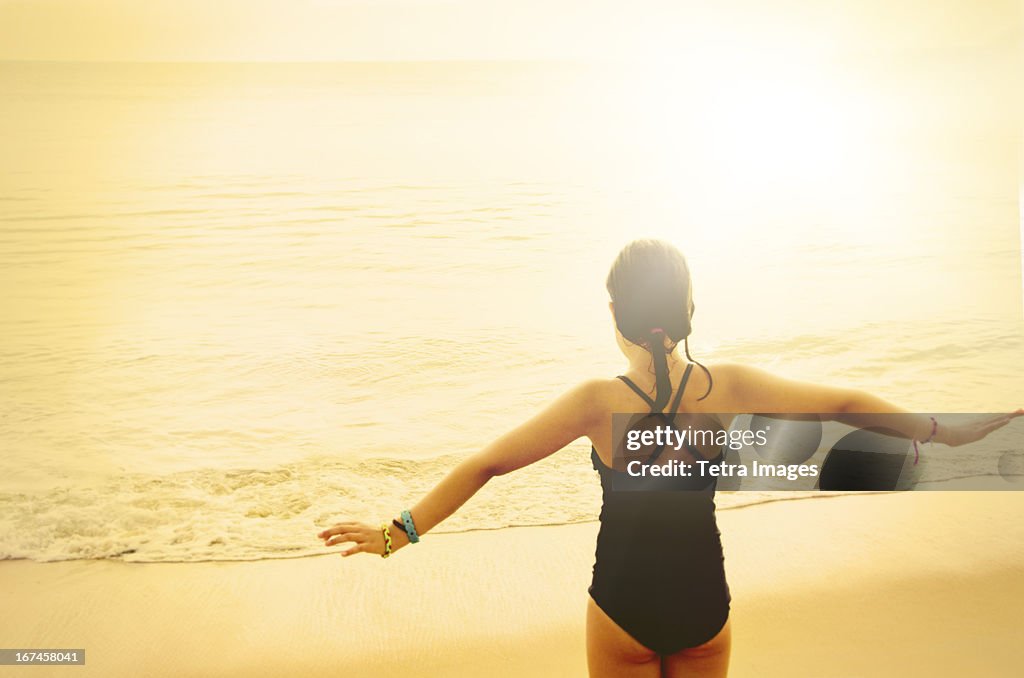 USA, North Carolina, Nags Head, Rear view of girl (8-9) standing with arms raised