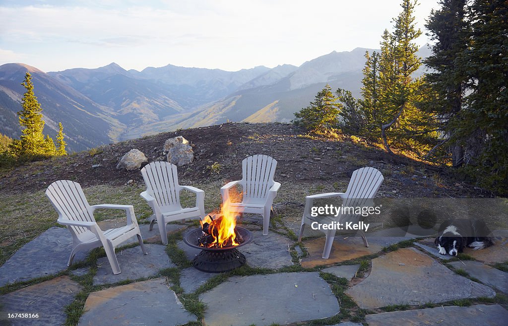 USA, Colorado, Dog lying down by fire pit and four empty chairs