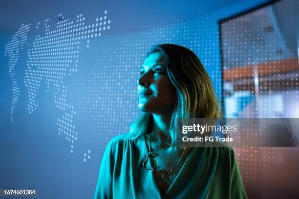 mature businesswoman looking to a hologram at office - technology montage stock pictures, royalty-free photos & images