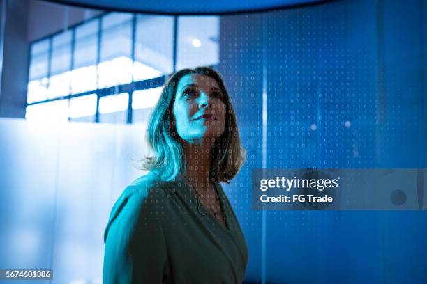 empresária madura olhando para um holograma no escritório - startup - fotografias e filmes do acervo