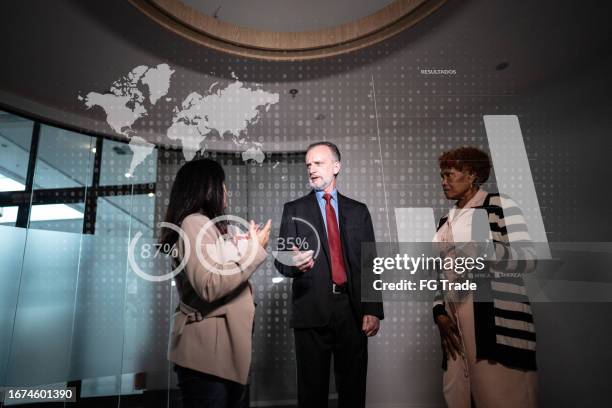 compañeros de trabajo mirando un holograma durante una reunión en la oficina - holographic-map fotografías e imágenes de stock