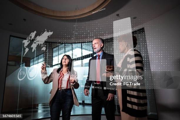 compañeros de trabajo mirando un holograma durante una reunión en la oficina - holographic-map fotografías e imágenes de stock