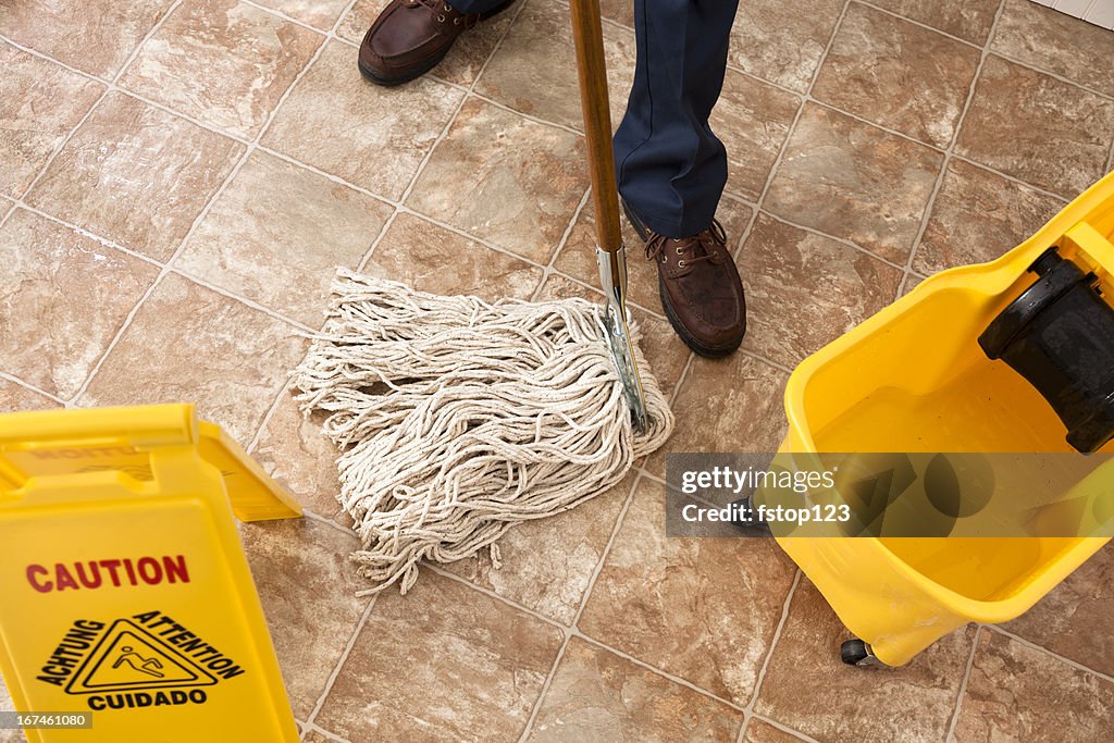 Caution sign, janitor man mopping floor of retail store. Cleaning.