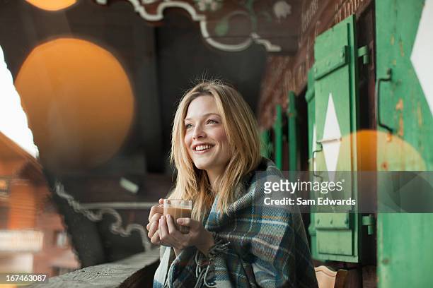 mujer sonriente envuelto en una manta y bebiendo café - hot blonde woman fotografías e imágenes de stock