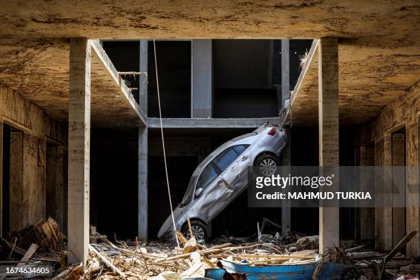 Tilted car sits above debris in Libya's eastern city of Derna on September 18 following deadly flash floods. A week after a tsunami-sized flash flood...