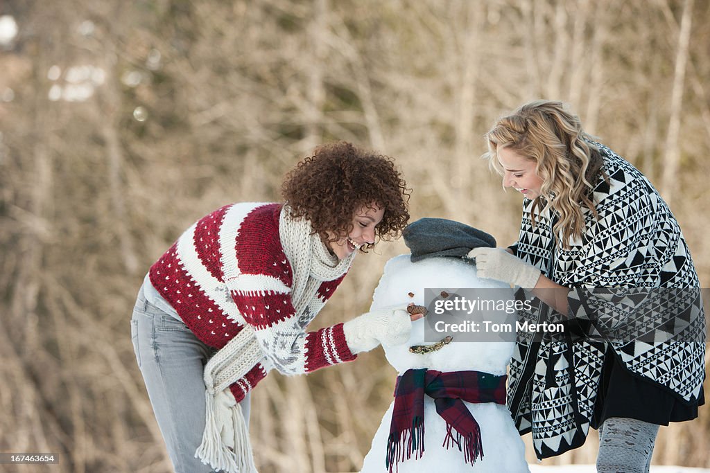 Two women building snowman