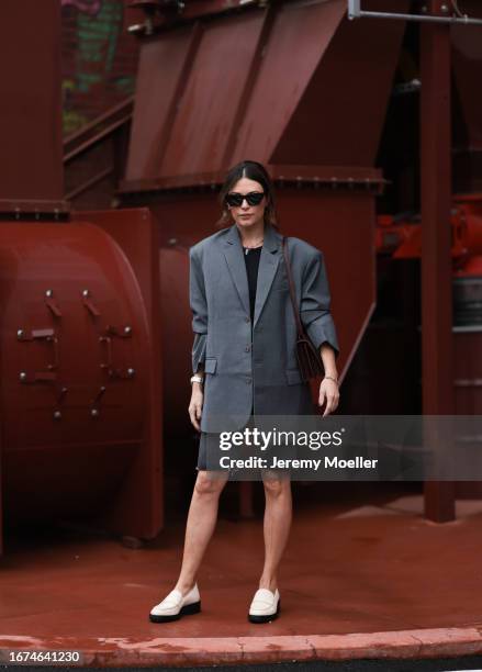 Ulla Johnson Fashion week guest is seen wearing white shoes, jeans shorts, an oversized blazer with brown buttonsand a black top, dark hades, a...