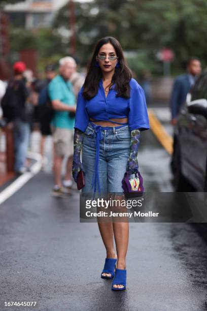 Ulla Johnson Fashion week guest Samia Laaboudi is seen wearing blue sandals, oversized denim jeans with fringes, a cropped blue blouse, blue and...