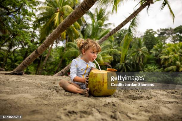a young girl drinking a fresh coconut through a straw. - 2 coconut drinks ストックフォトと画像