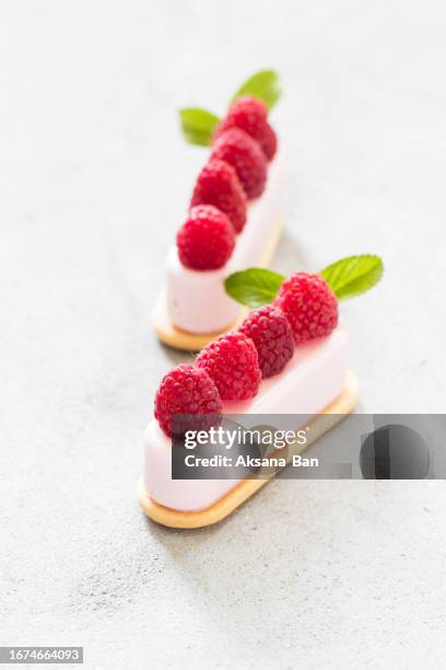 vegan dessert. raspberry cream cakes on cookies, decorated with fresh raspberries. light grey background - cream cake stock pictures, royalty-free photos & images