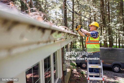 Storm damage and photo fixation after storm: engineer in protective wear photographing collapsed house roof. Focus on inspector Storm damage and photo fixation after storm: engineer in protective wear photographing collapsed house roof. Focus on inspector