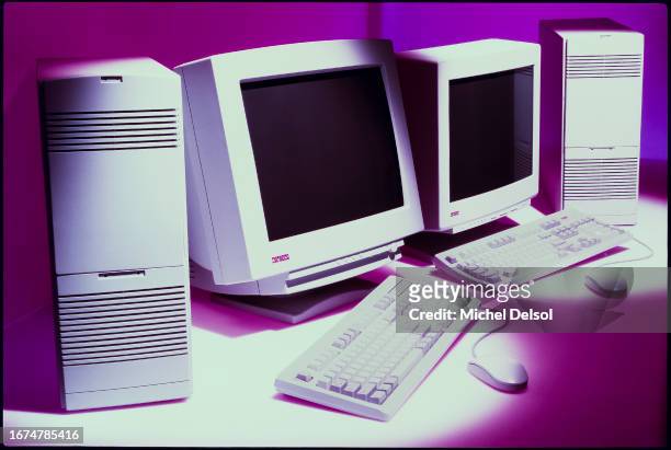 Two Digital Computers with monitors, towers, keyboards and mouses on a purple background. Photo by Michel Delsol/Getty Images.