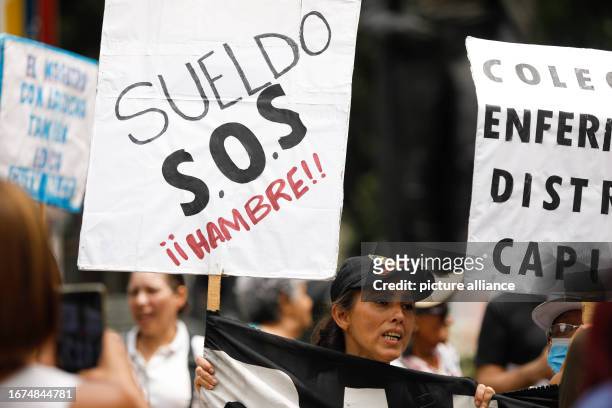 September 2023, Venezuela, Caracas: "Salary - S.O.S - Hunger!!!" reads a woman's placard during a protest for fair incomes. Demonstrators criticized...