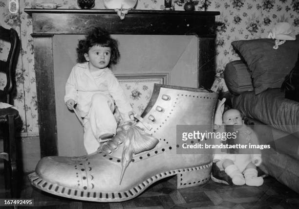 Infant and a baby with an oversized shoe for Christmas. 1936. Photograph. Ein Kleinkind und ein Baby mit einem übergroßen Schuh zu Weihnachten. 1936....