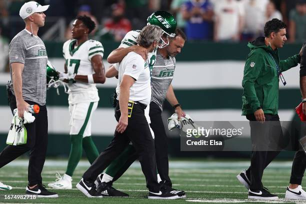 Quarterback Aaron Rodgers of the New York Jets is helped off the field by team trainers after an injury during the first quarter of the NFL game...