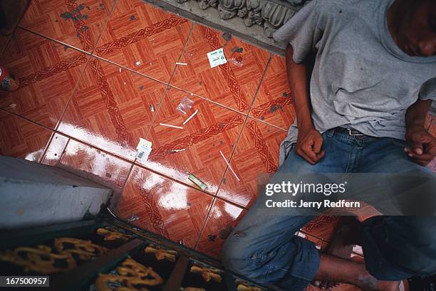 Teenage street kid and methamphetamine addict lolls in a stupor after smoking the drug at a temple in Phnom Penh. Around him lie straws through which...